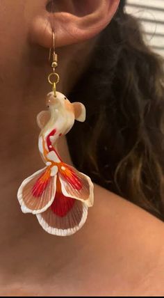 a close up of a woman's neck wearing earrings with flowers on it and a bird hanging from the back