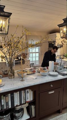 a man preparing food in a kitchen with lots of counter space and lights hanging from the ceiling