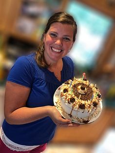 a woman holding a cake with sunflowers on it in front of the camera