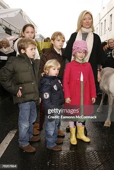 a group of people standing next to each other in front of a building with donkeys