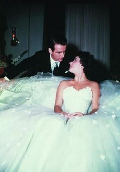 a man and woman in wedding dresses sitting next to each other