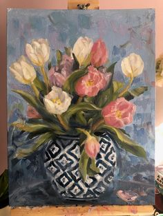 a painting of tulips in a blue and white vase on an easel