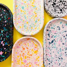 four plates with different designs on them sitting on top of a yellow surface, one has sprinkles and the other is black