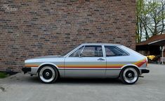 an old car parked in front of a brick building with white rims and yellow stripes