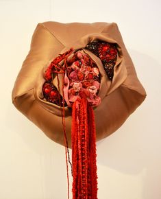 a brown bag with red tassels hanging from it's side on a wall