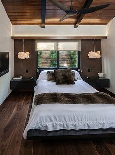 a large bed in a bedroom next to a flat screen tv on top of a wooden floor