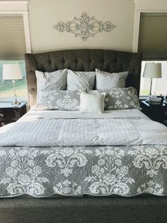 a bedroom with a large bed and two nightstands next to each other in front of a window