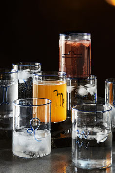 several glasses filled with liquid sitting on top of a black counter next to each other