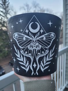 a person holding up a cup with a moth on it's side and stars in the background