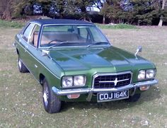 a green car is parked in the grass