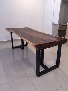 a wooden table sitting on top of a white tiled floor next to two black metal legs