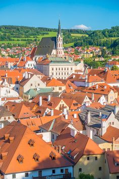 an aerial view of a city with red roofs and green hills in the back ground