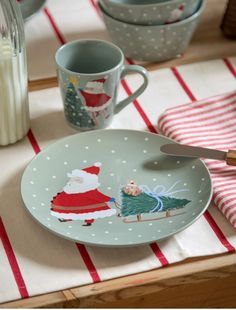 a plate with santa clause on it sitting on a table next to two mugs