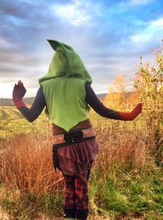 a person in a costume standing on a dirt road with their arms out to the side