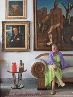 a woman sitting on a couch in front of paintings