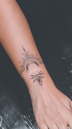 a woman's arm with a sun and moon tattoo on the left side of her wrist