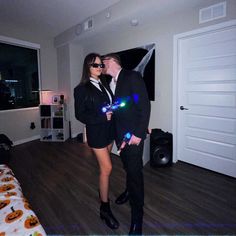 a man and woman dressed up in black clothes standing next to each other on a wooden floor