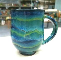 a blue and green coffee cup sitting on top of a table