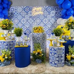 blue and yellow decorations are on display in front of a birthday backdrop with balloons, flowers, and teapots