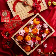 an arrangement of oranges and other decorations on a red table cloth with gold ornaments