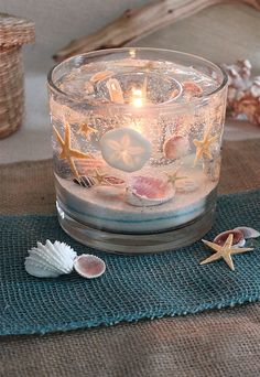 a candle that is sitting on top of a table next to some seashells