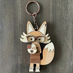 a wooden keychain with an image of a fox wearing glasses and holding a piece of wood