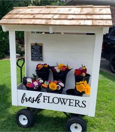 flowers are on display at the flower stand in front of a building with a sign that says fresh flowers