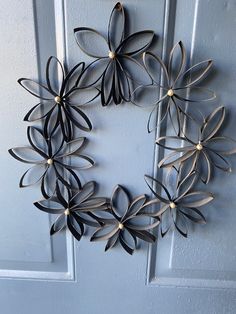 a metal wreath hanging on the front door with black and white flowers attached to it