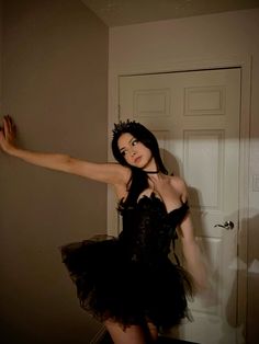 a woman in a black dress is posing for the camera with her arms stretched out