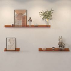 three wooden shelves with vases and other items on them in a white walled room