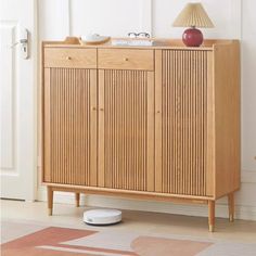 a wooden cabinet sitting on top of a floor next to a lamp