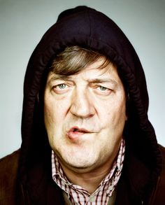 a man wearing a hoodie looking at the camera with an angry look on his face