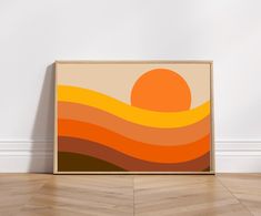 an orange and yellow abstract painting hangs on the wall in front of a white wall