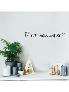 a white shelf topped with potted plants next to a wall that says if not now when?