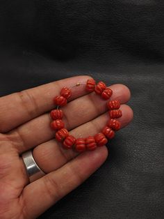 a hand holding a red beaded bracelet in it's palm with a silver ring