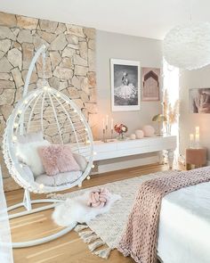 a bedroom with a hanging chair, bed and pictures on the wall above it is decorated in pink and white