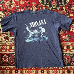 a blue nirvana t - shirt sitting on top of a rug