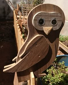 a wooden owl sitting on top of a planter