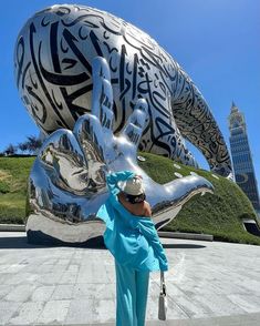 a woman standing in front of a large metal sculpture with an elephant on it's back