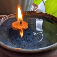 a lit candle sitting in a bowl on top of a table