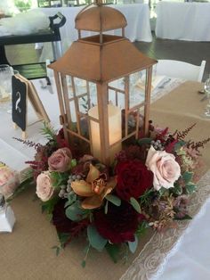 a table with a lantern, flowers and candles on it for a centerpiece or decoration