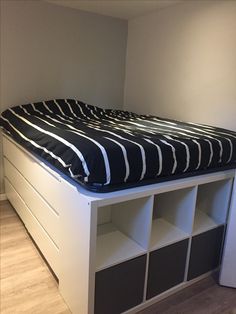 a bed with black and white stripes on it, next to a bookcase in the corner