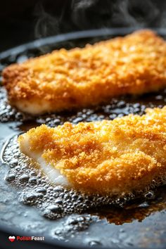 two fried fish fillets cooking in a frying pan