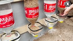 three soda bottles are hanging from the side of a building and one is filled with rice