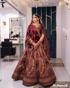 a woman in a red and gold bridal gown standing in front of a mirror