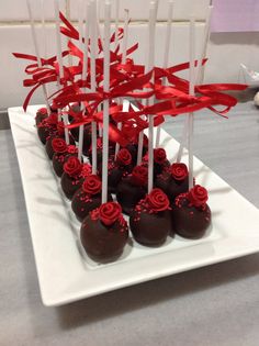 there are many chocolates on the white plate with red ribbons and bows around them