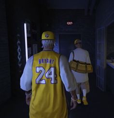 two people in yellow and white uniforms walking down a hallway with one person wearing a baseball uniform