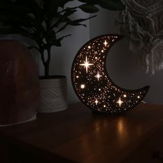 a wooden table topped with a moon and stars light up the night sky next to a potted plant