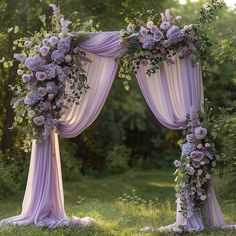 an outdoor wedding arch decorated with purple flowers and greenery