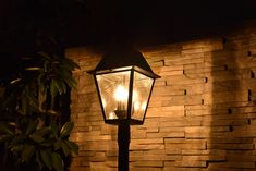 a street light is lit up in front of a brick wall